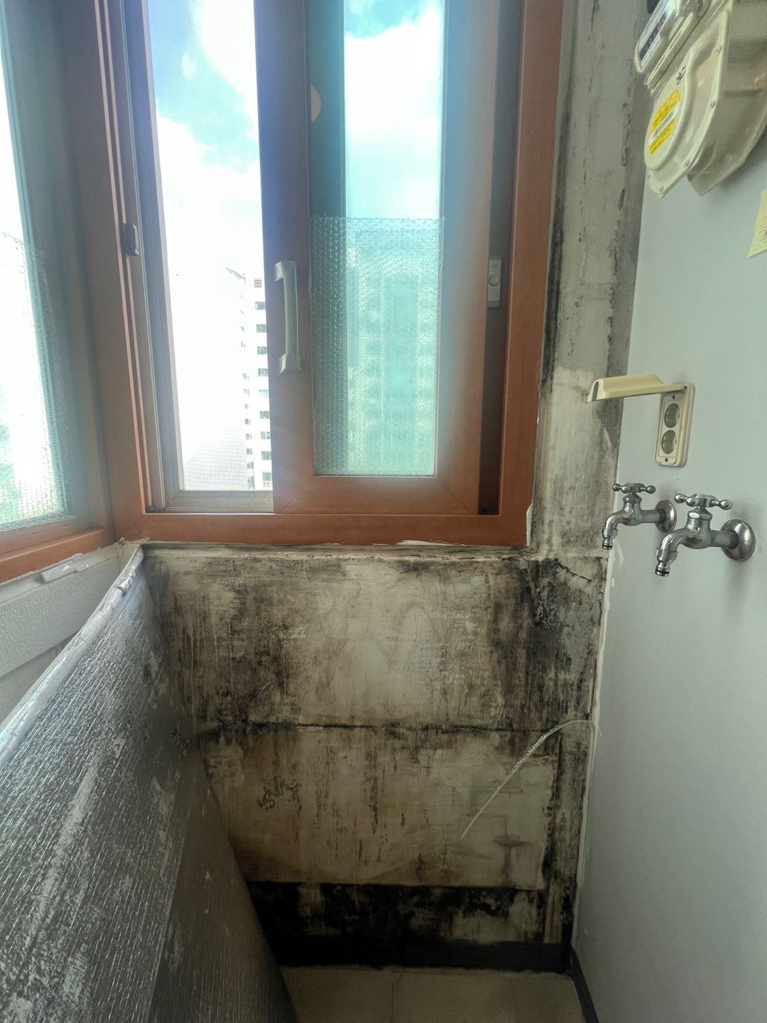 곰팡이와 결로 자국이 번진 구축 아파트 발코니 벽면